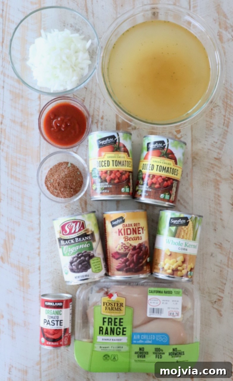 Creamy Chicken Enchilada Crockpot Feast 3 A vibrant collection of ingredients for chicken enchilada soup artfully arranged on a rustic white wooden board, showcasing fresh and canned components.