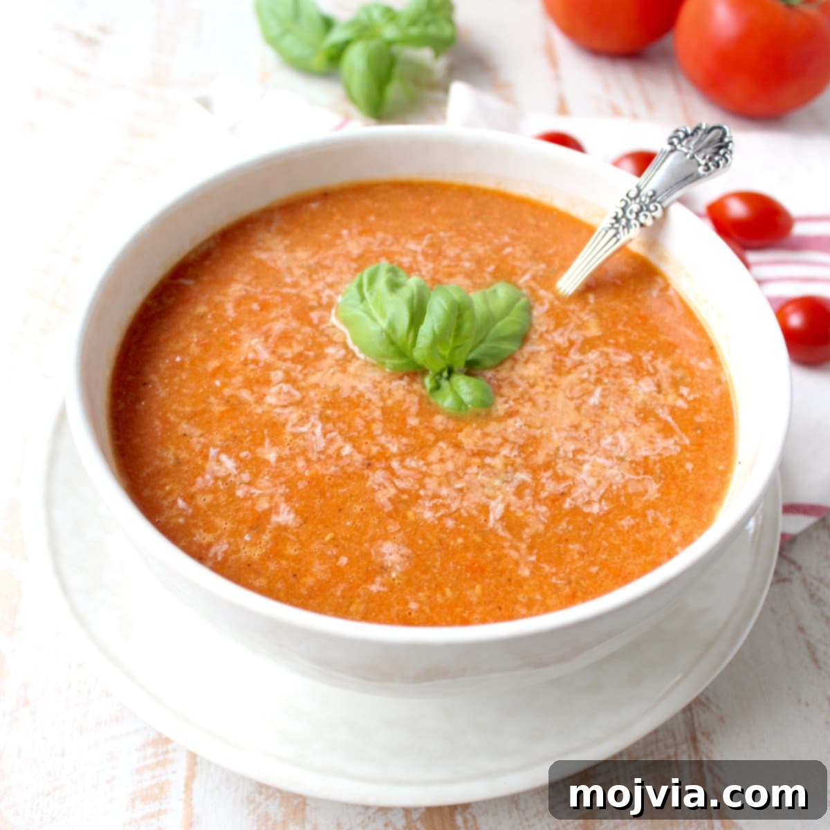 Fire-Kissed Tomato Bisque 2 tomato soup in bowl with spoon and basil leaves