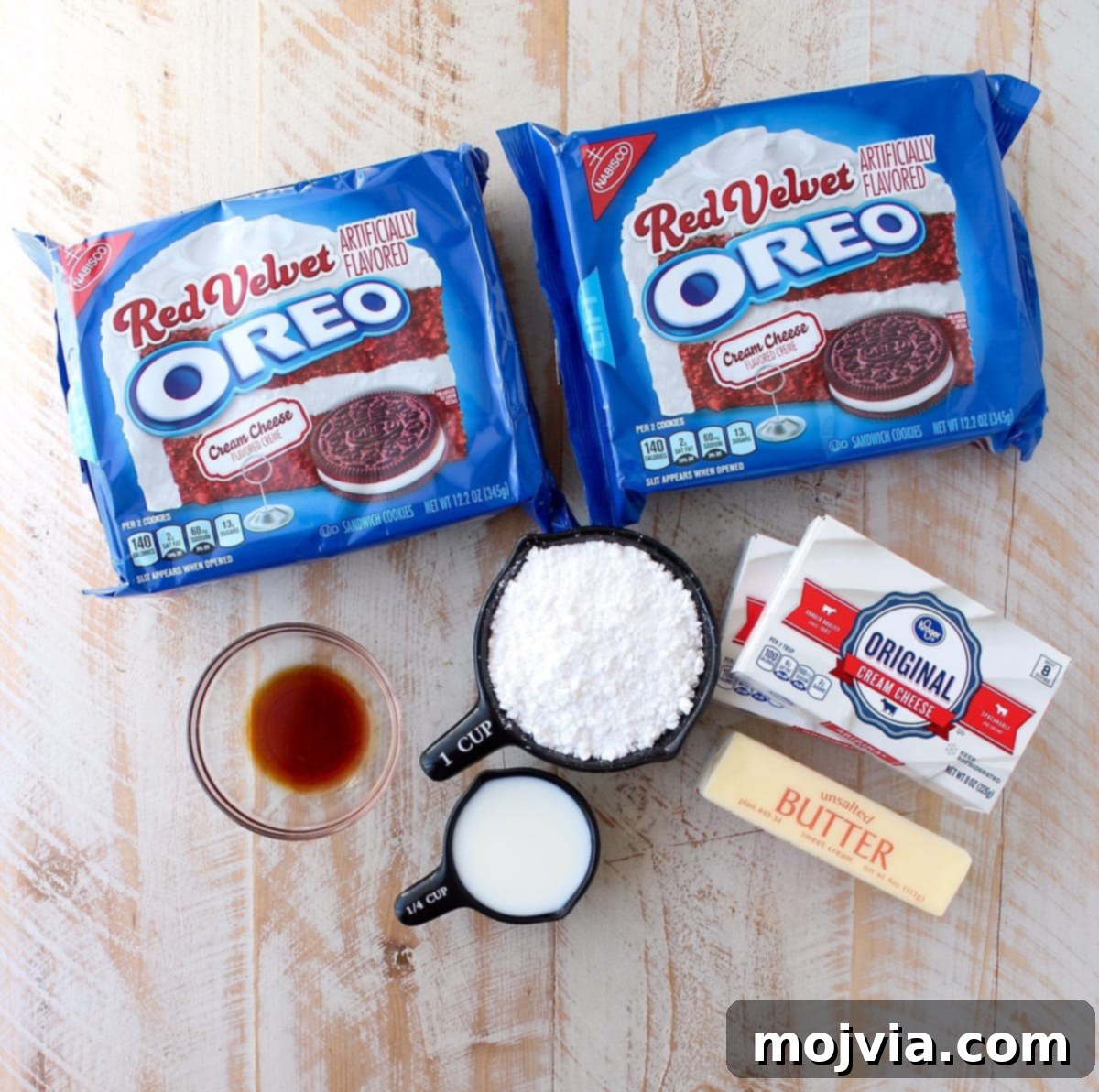 Close-up of a perfectly cut Red Velvet Oreo cheesecake bar, revealing the thick, bright red cookie crust and the creamy, flecked cheesecake filling.