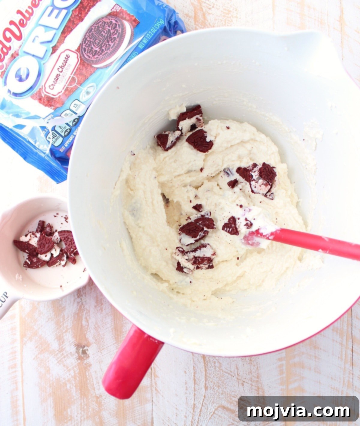 Creamy white cheesecake filling, studded with broken pieces of Red Velvet Oreos, ready to be spread over the chilled crust.