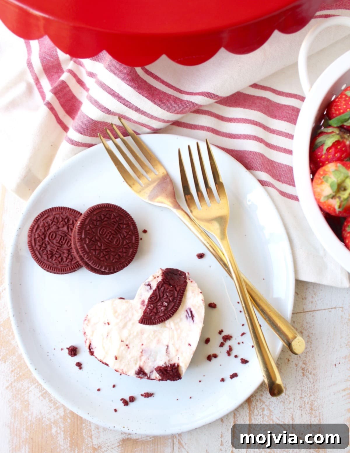 A tray of Red Velvet Oreo cheesecake bars, some cut into squares and others into heart shapes, showcasing the versatility of the dessert.