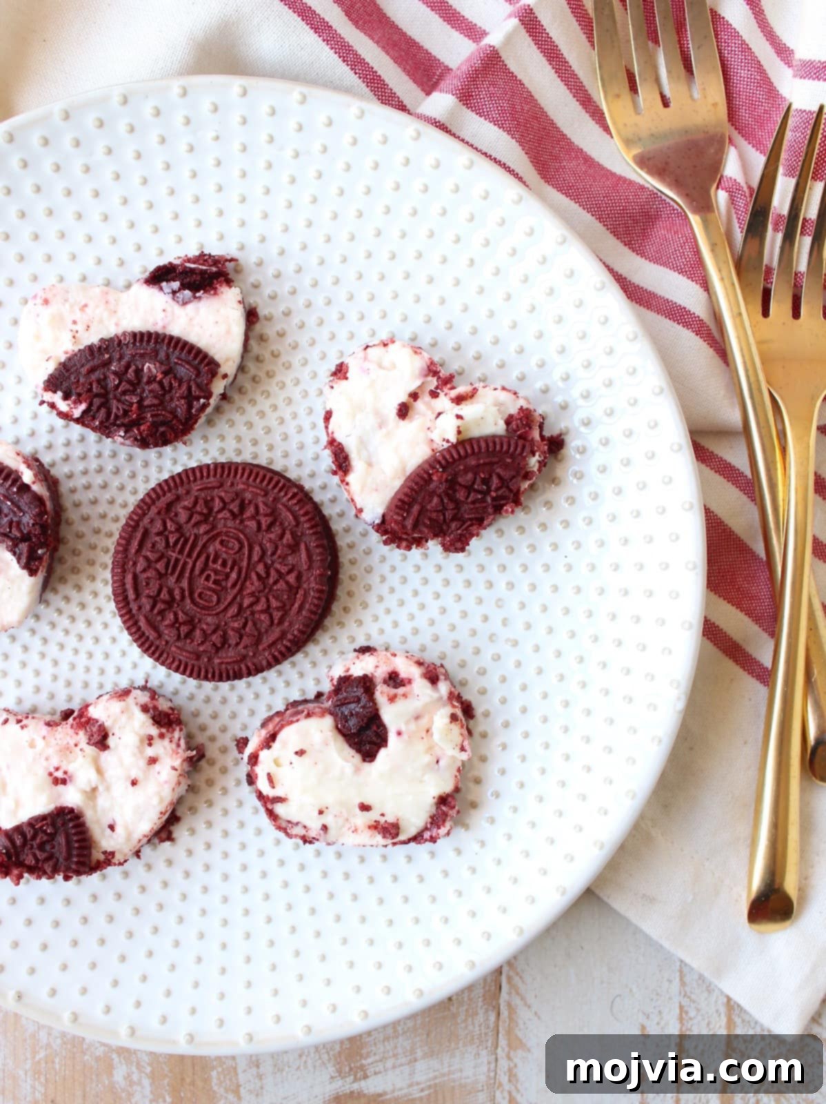 Assortment of heart-shaped Red Velvet Oreo cheesecake bars, varying in size, displayed beautifully on a serving platter.