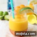 A vibrant yellow Frozen Mango Margarita in a glass, garnished with a lime wedge, promising a delicious and refreshing tropical experience.
