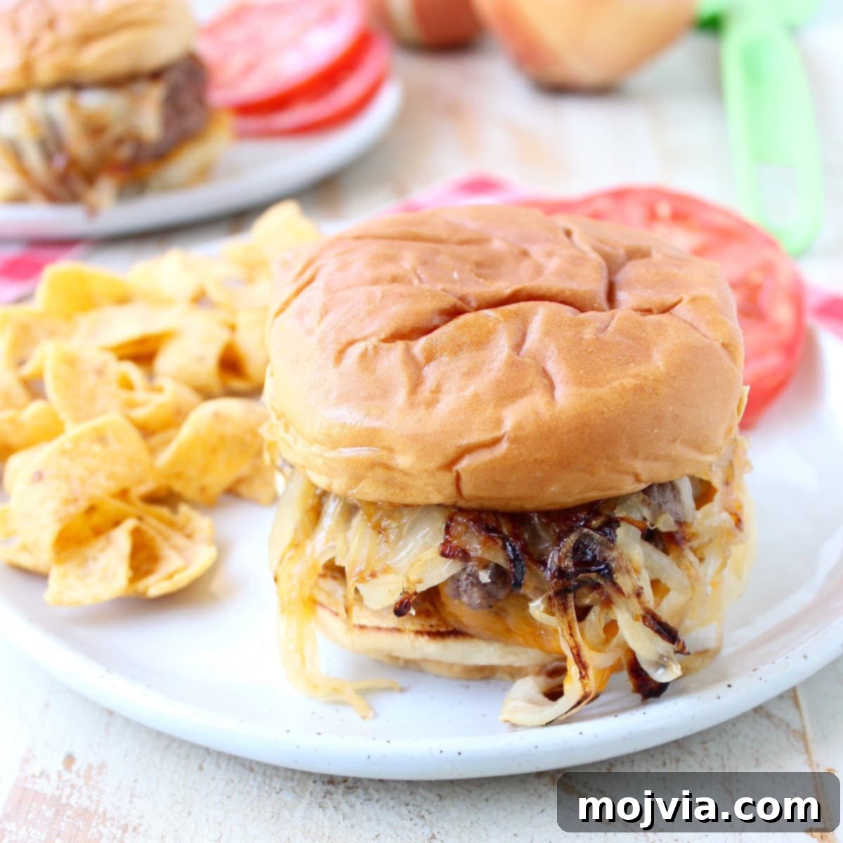 Oklahoma Onion Smash Burger 2 Classic Oklahoma Fried Onion Burger served on a plate with crispy Fritos chips and fresh sliced tomatoes, highlighting its rustic appeal