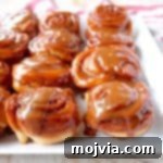 Salted Caramel Cinnamon Rolls, golden brown with gooey caramel, presented on a white plate.