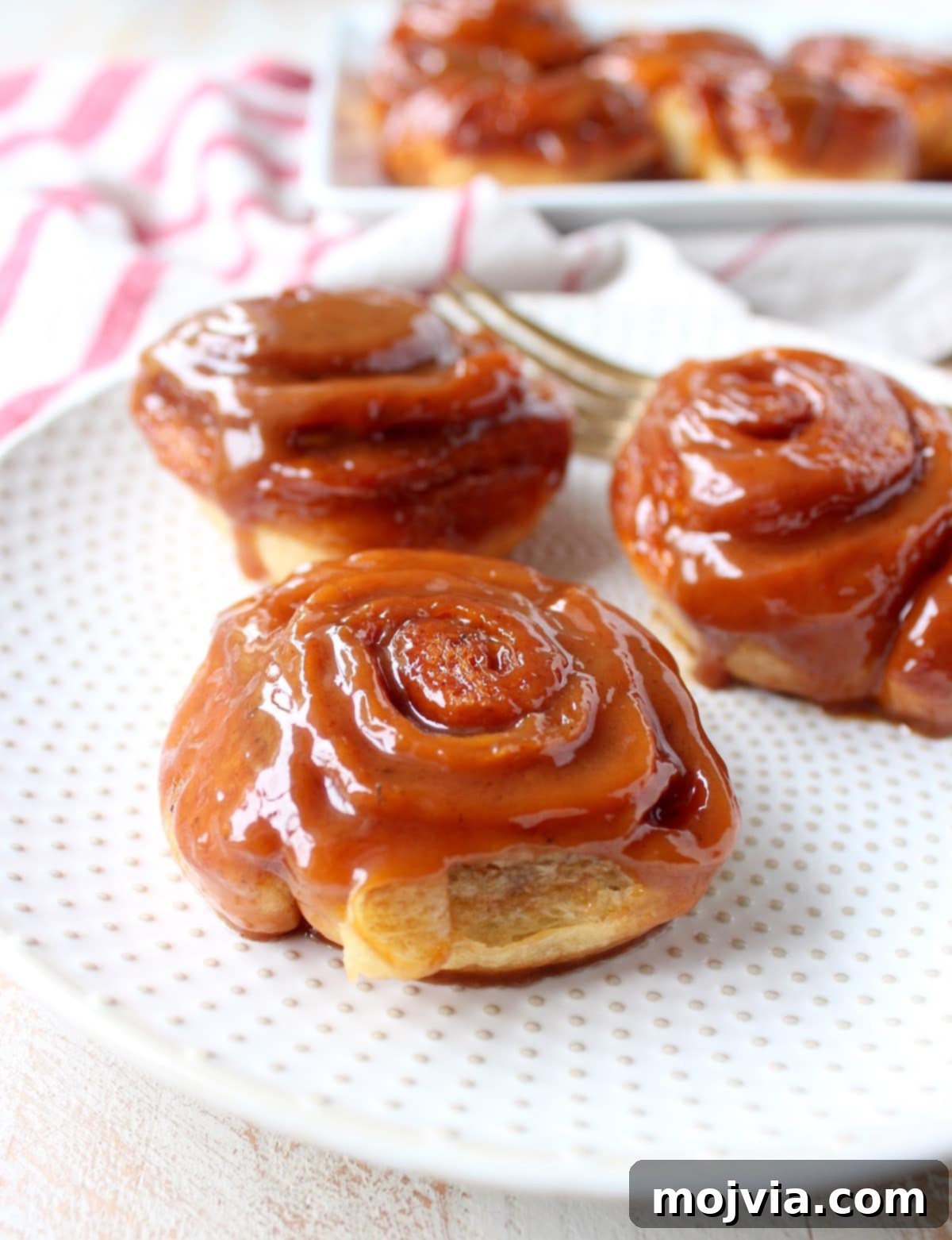 A close-up of a single Salted Caramel Cinnamon Roll, showing the beautiful swirled layers and the generous drizzle of caramel, ready to be picked up.