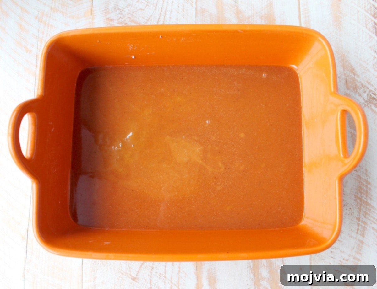 Rich, amber salted caramel sauce freshly poured into an orange baking dish, ready for the cinnamon rolls.