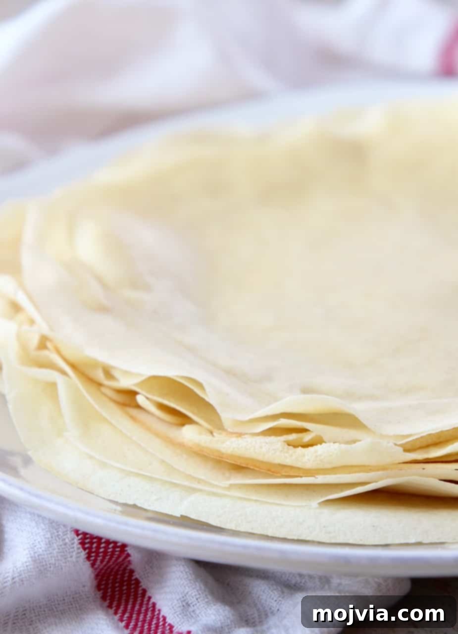 Authentic French Crepes Made Easy 2 crepes stacked on top of each other on a plate