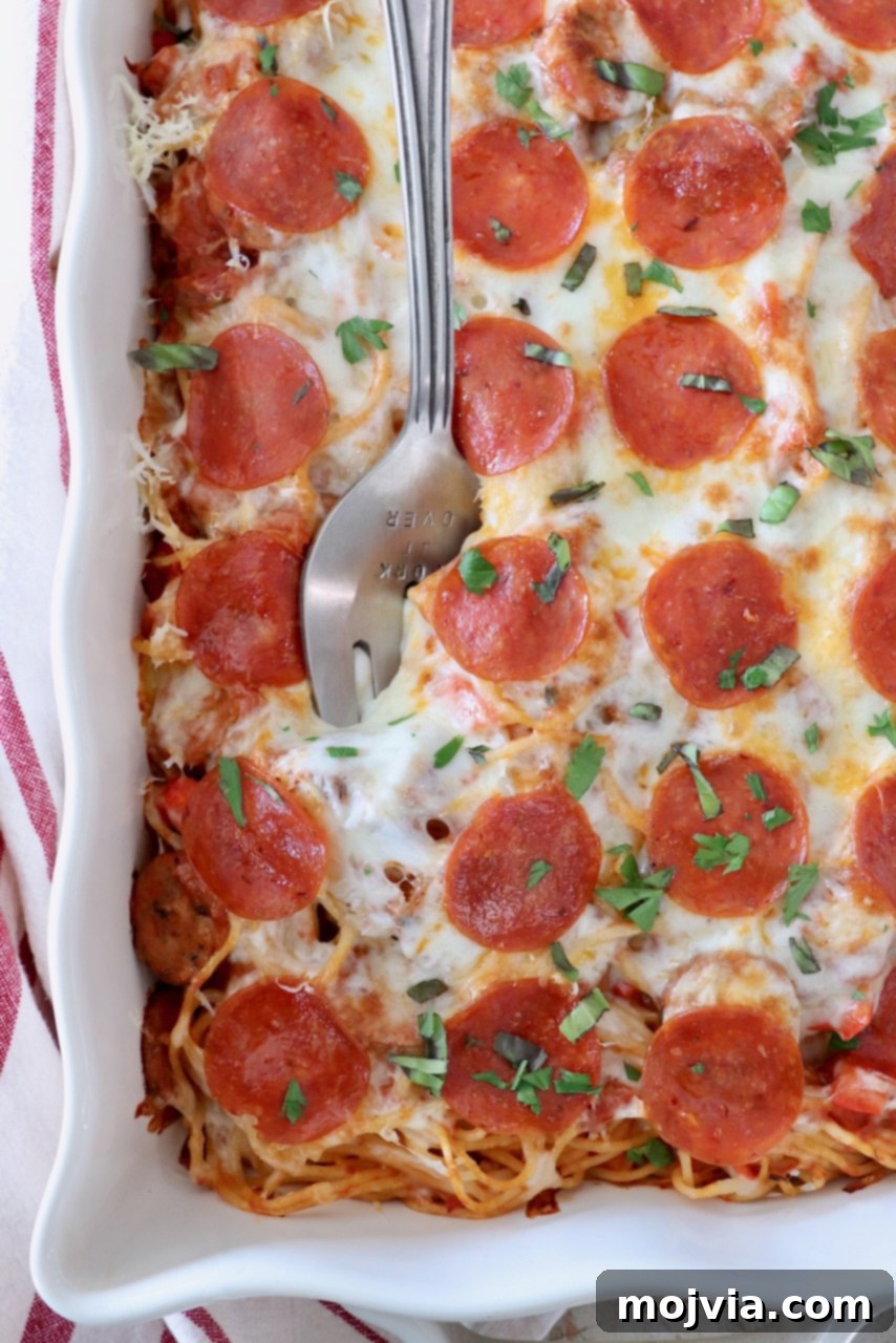 Ultimate Pizza Spaghetti Casserole 2 A delicious pizza baked spaghetti casserole in a baking dish, ready to be served, with a large serving fork.