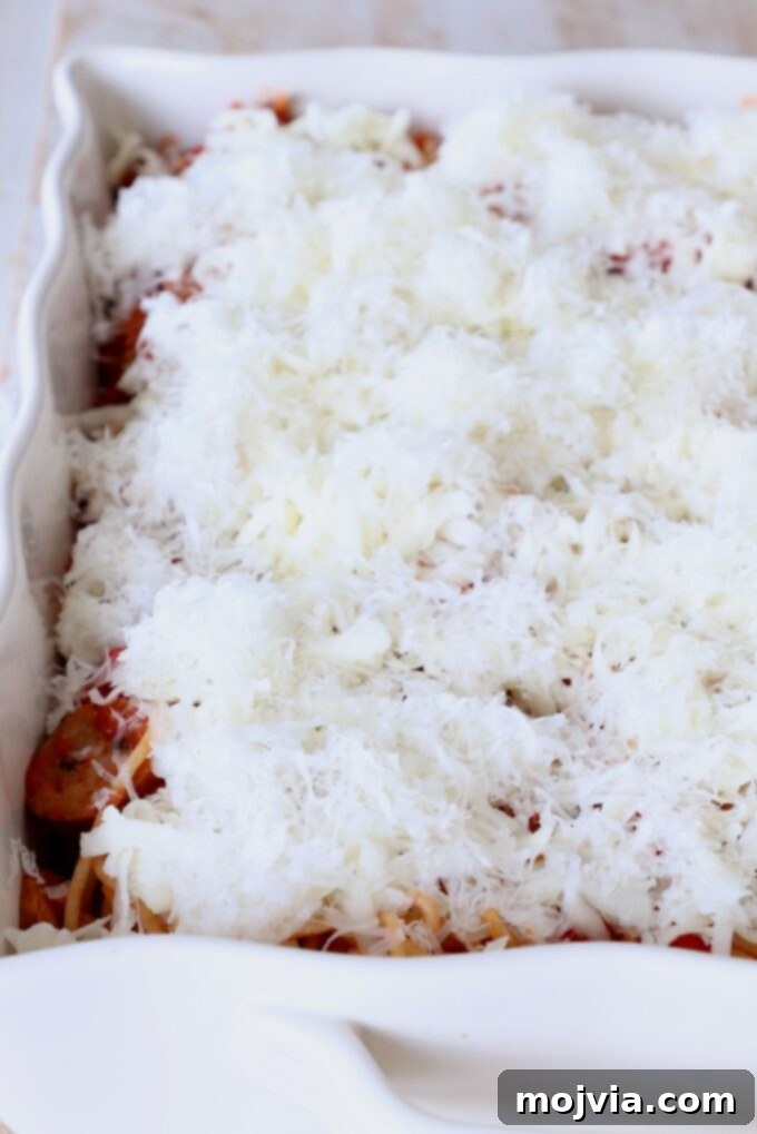 Ultimate Pizza Spaghetti Casserole 6 Uncooked spaghetti casserole generously topped with shredded mozzarella and Parmesan cheese, awaiting pepperoni slices.