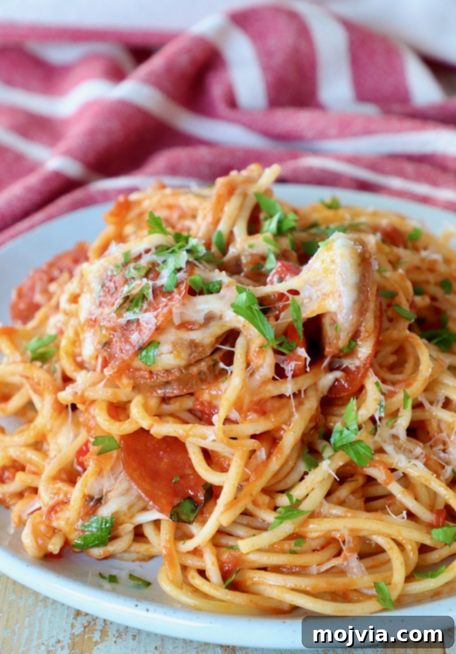 Ultimate Pizza Spaghetti Casserole 9 A serving of pizza baked spaghetti on a white plate, garnished and ready to be enjoyed.