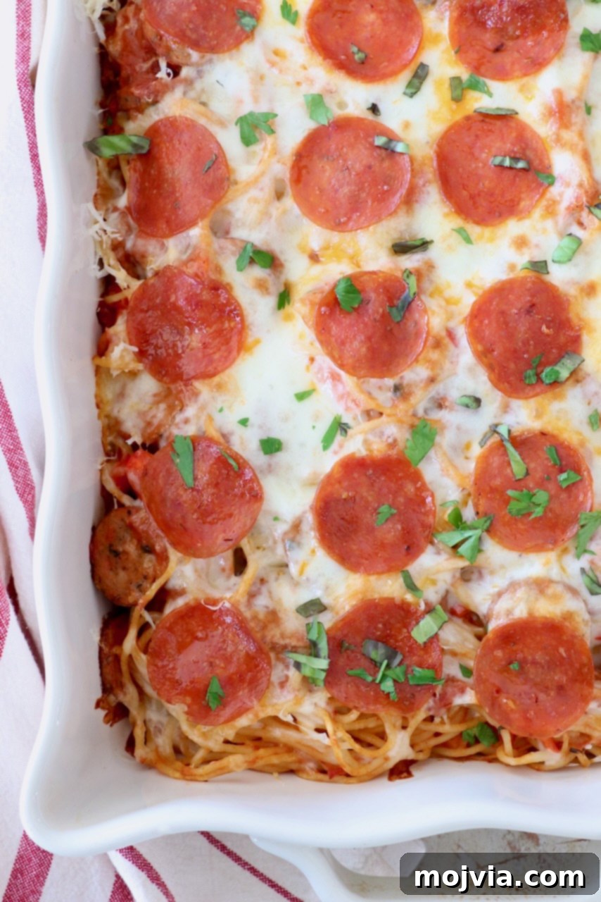 Ultimate Pizza Spaghetti Casserole 10 Close-up of baked spaghetti in a casserole dish, topped with bubbling melted cheese and perfectly cooked pepperonis.