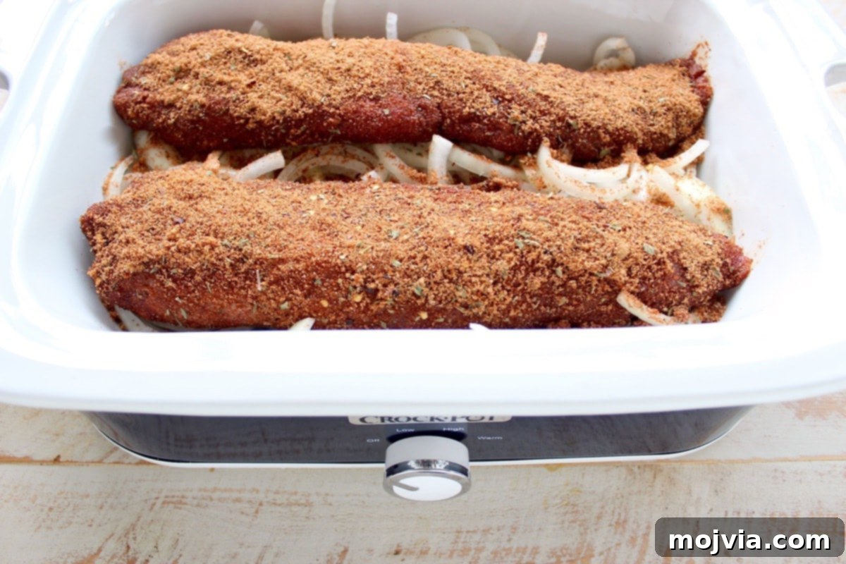 Sweet and Smoky Dr Pepper Pulled Pork Sliders 4 Two pork loins coated in a dry rub on top of onions in a slow cooker, ready for sauce.