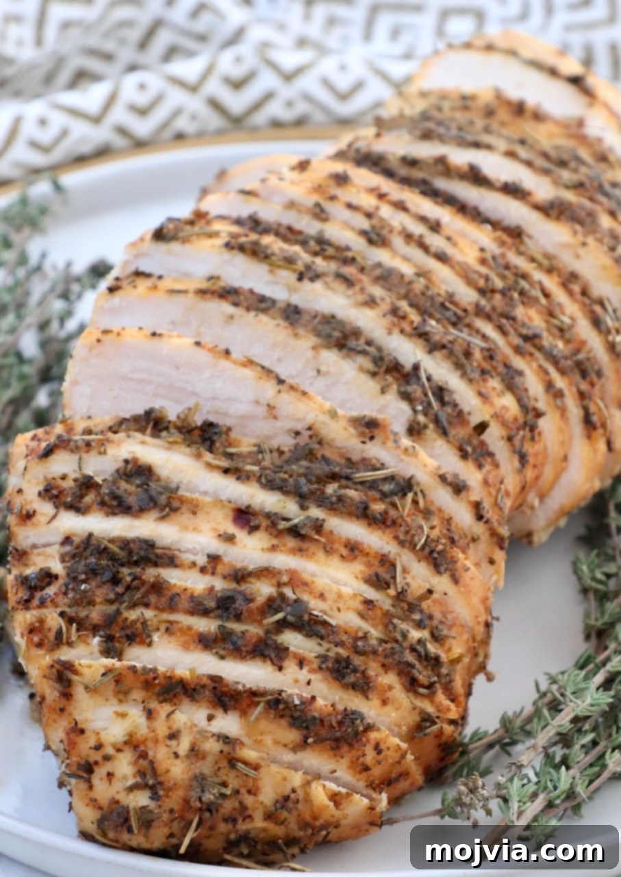 Melt-in-Your-Mouth Slow Cooker Turkey 2 Sliced slow cooker turkey breast on a plate with fresh thyme garnish, highlighting its juicy texture.