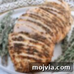 Melt-in-Your-Mouth Slow Cooker Turkey 12 Sliced slow cooker turkey breast on a plate with fresh thyme