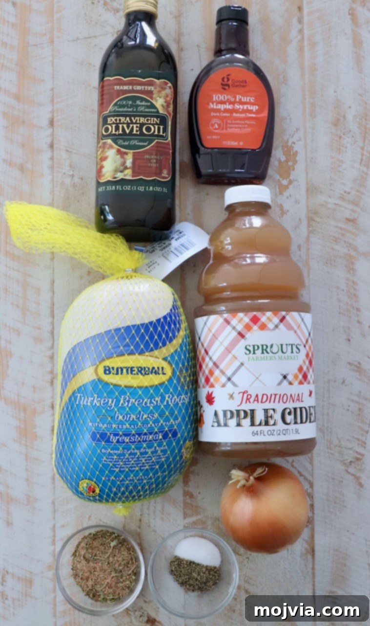 Melt-in-Your-Mouth Slow Cooker Turkey 3 A collection of fresh ingredients for maple apple turkey breast laid out on a white wooden board, including a turkey breast, apple cider, maple syrup, onion, olive oil, and various spices.