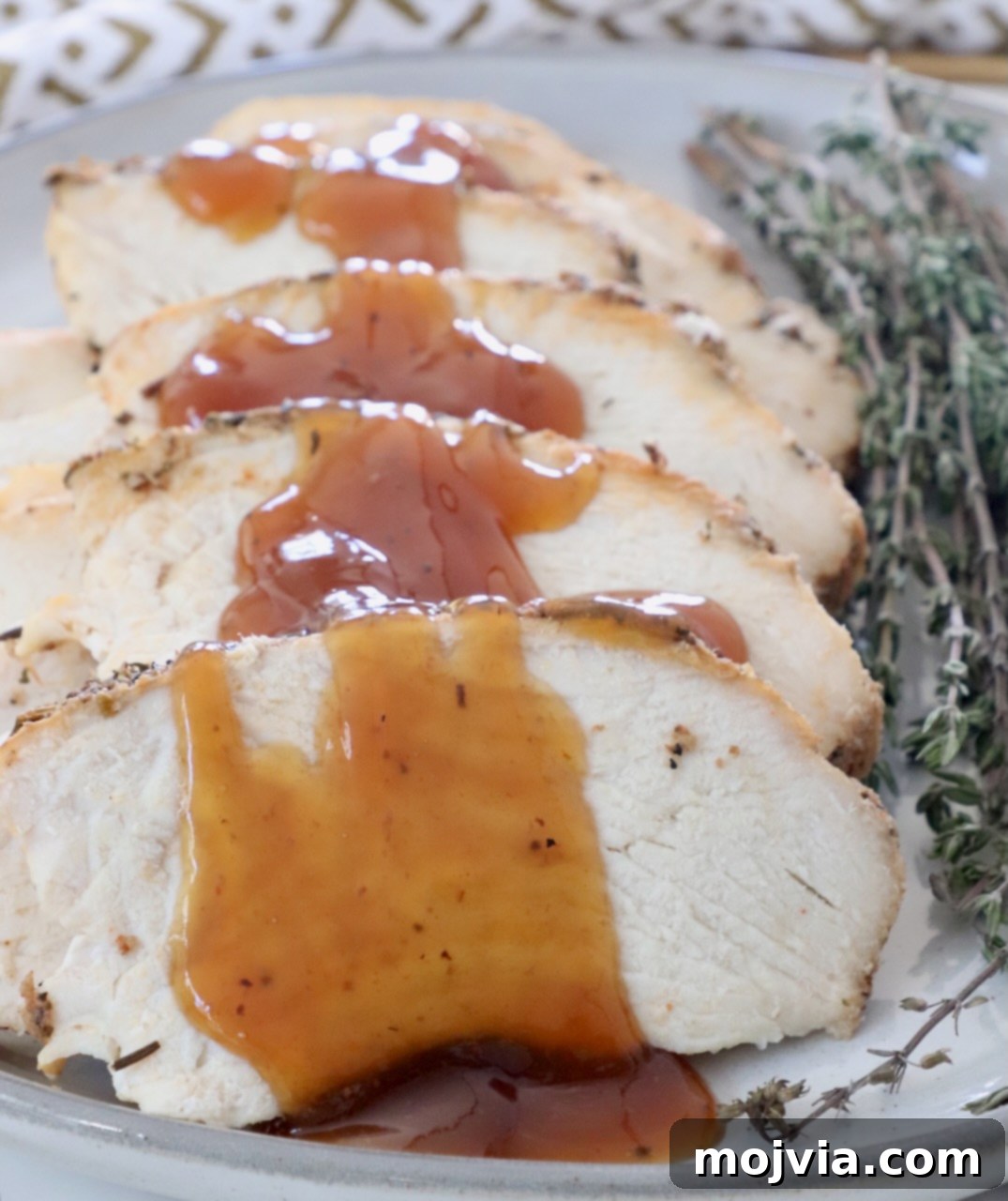 Melt-in-Your-Mouth Slow Cooker Turkey 10 Slices of slow cooker turkey breast arranged on a plate, beautifully drizzled with the sweet and savory maple apple glaze, ready to be served.