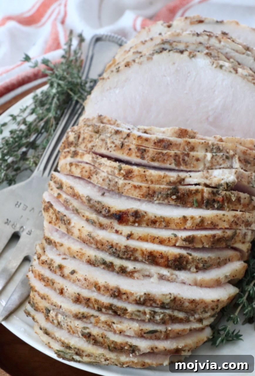Perfectly sliced sous vide turkey breast on a elegant plate, garnished with fresh thyme sprigs and a serving fork ready for holiday dinner.