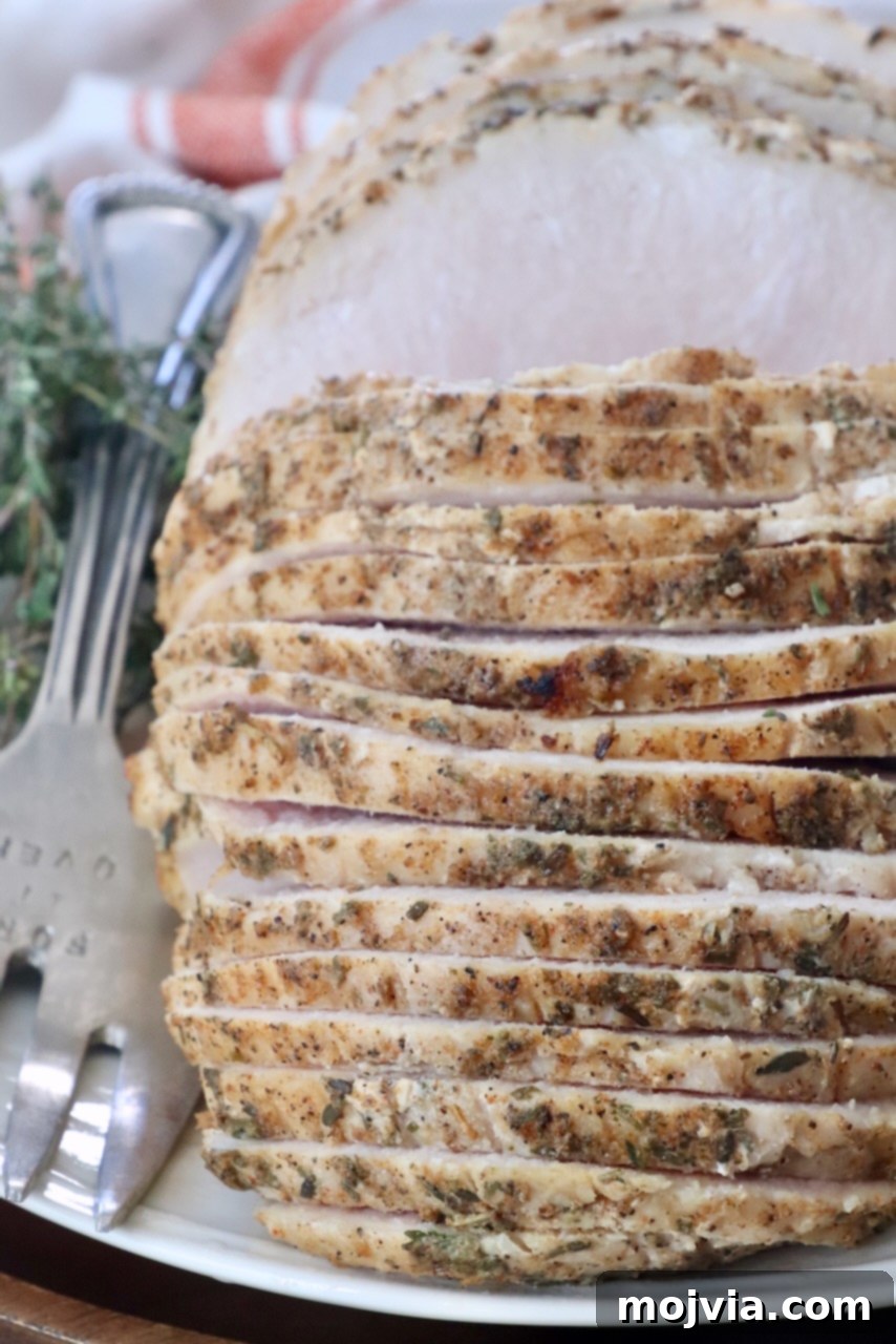 Succulent slices of sous vide turkey breast arranged on a plate with a large serving fork, highlighting its tender texture.