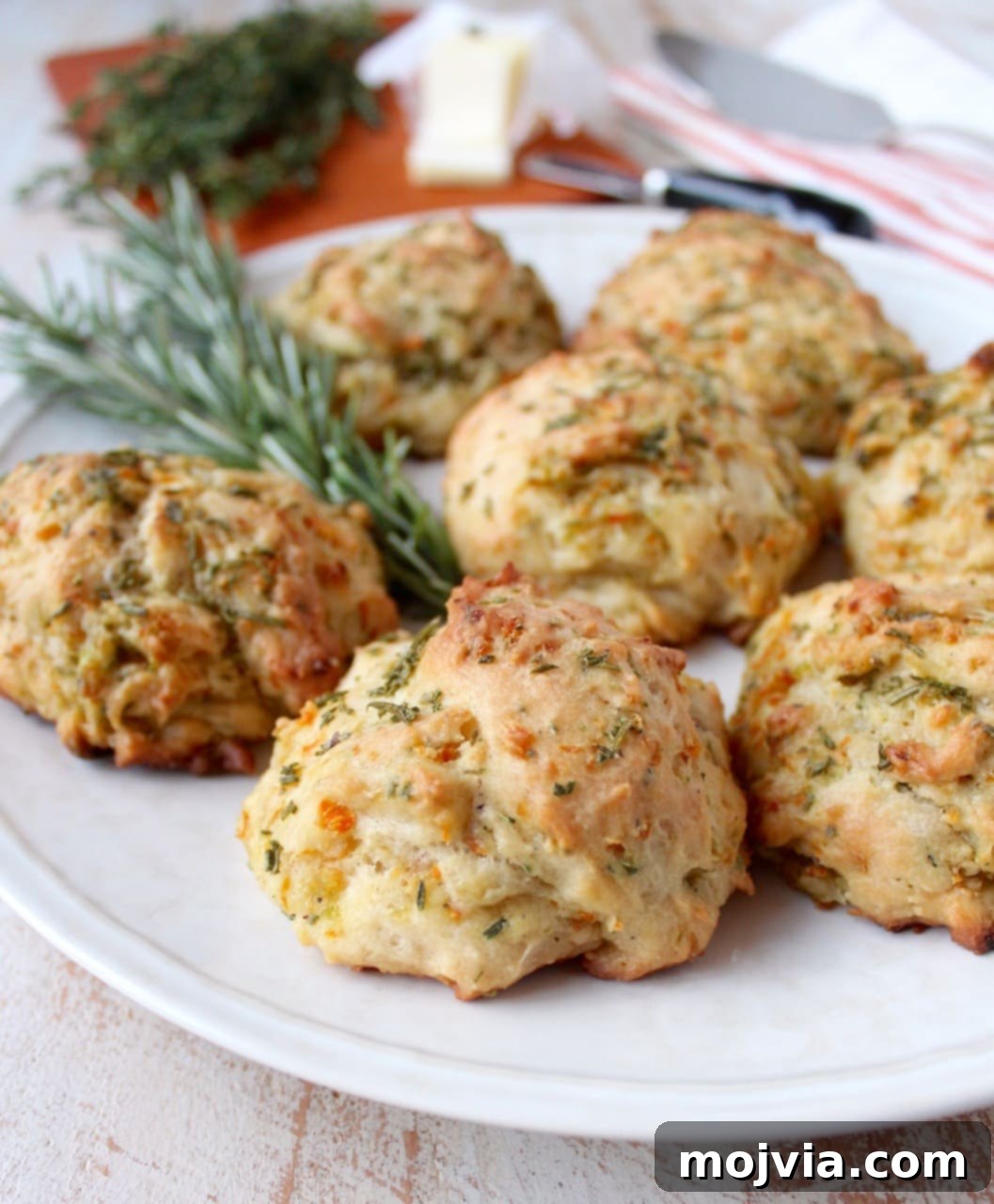 Savory Stuffing Biscuits 2 Golden-brown stuffing biscuits arranged on a plate with fresh rosemary sprigs.