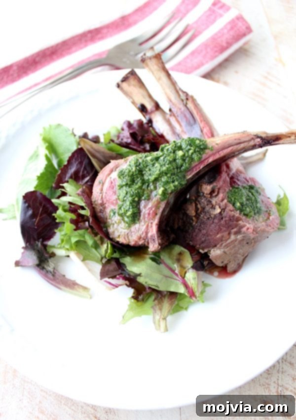 Succulent Herb Butter Roasted Lamb with Vibrant Mint Chimichurri 6 Individual double lamb chops, artfully arranged on a bed of fresh salad greens and topped with mint chimichurri, ready for serving.