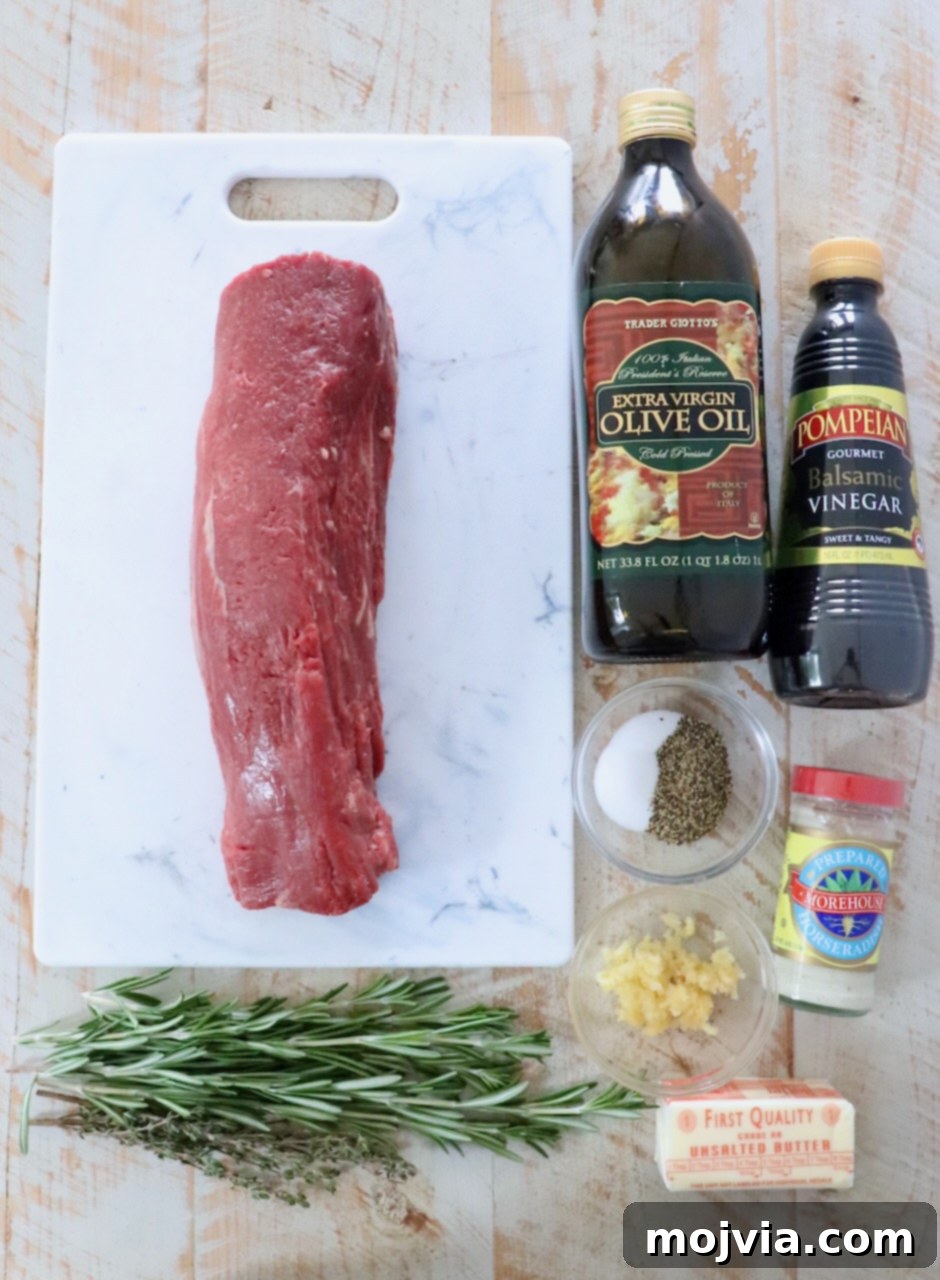 Fresh ingredients for herb crusted beef tenderloin laid out on a white wooden board.