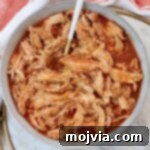 Spicy Shredded Instant Pot Buffalo Chicken 10 Shredded chicken in buffalo sauce in a bowl with a fork