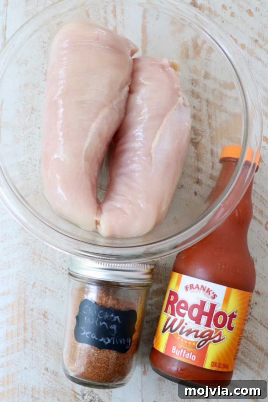 Spicy Shredded Instant Pot Buffalo Chicken 3 Ingredients for Instant Pot Buffalo Chicken laid out on a white wood board