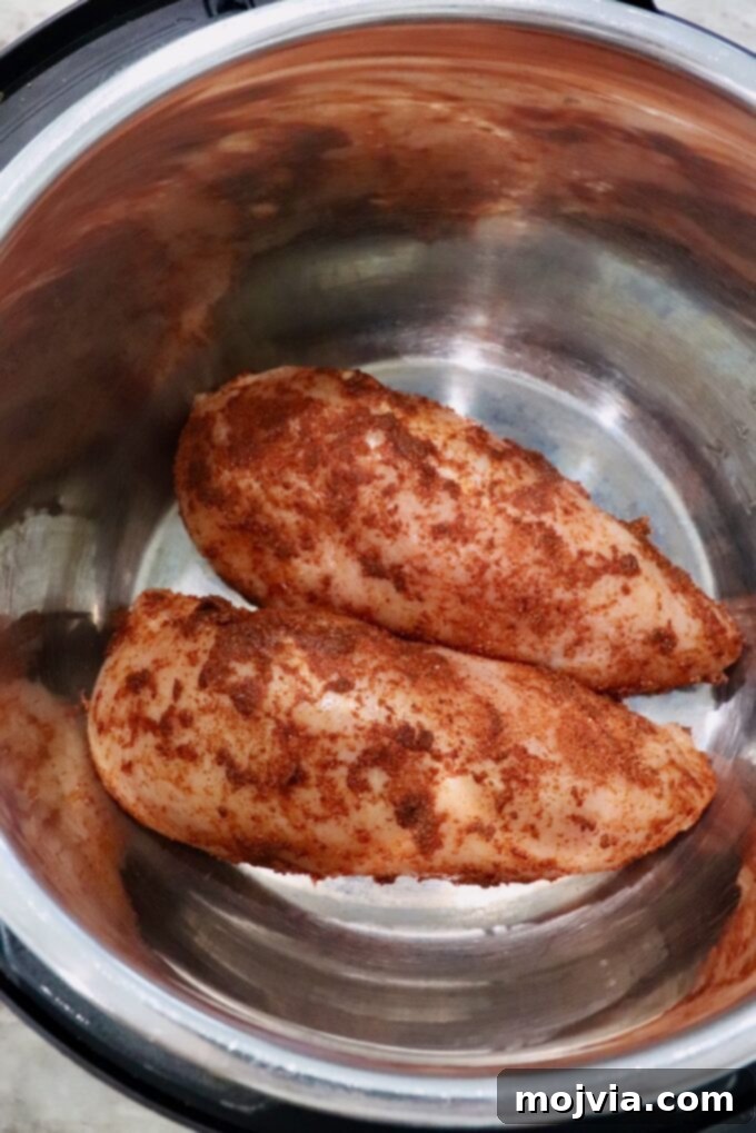 Spicy Shredded Instant Pot Buffalo Chicken 4 Seasoned chicken breasts placed in an Instant Pot