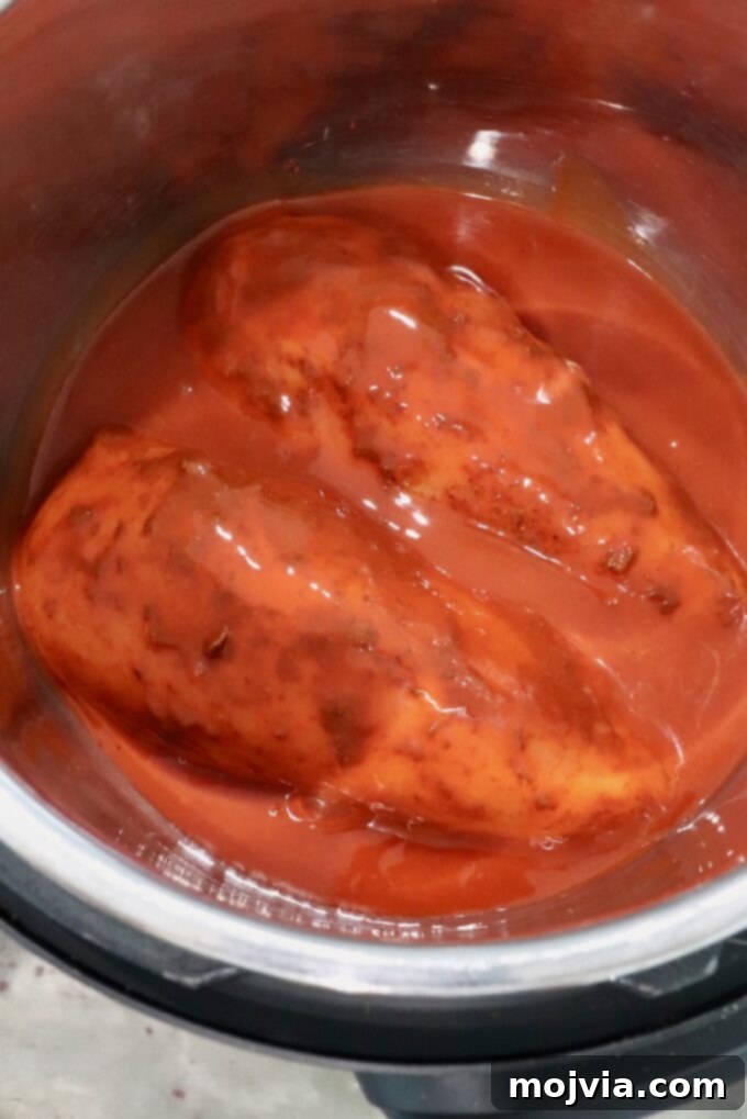 Spicy Shredded Instant Pot Buffalo Chicken 5 Seasoned chicken breasts covered in buffalo sauce in an Instant Pot