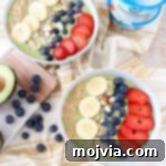 A small, artfully arranged avocado smoothie bowl, topped with a variety of fresh fruits and nuts.