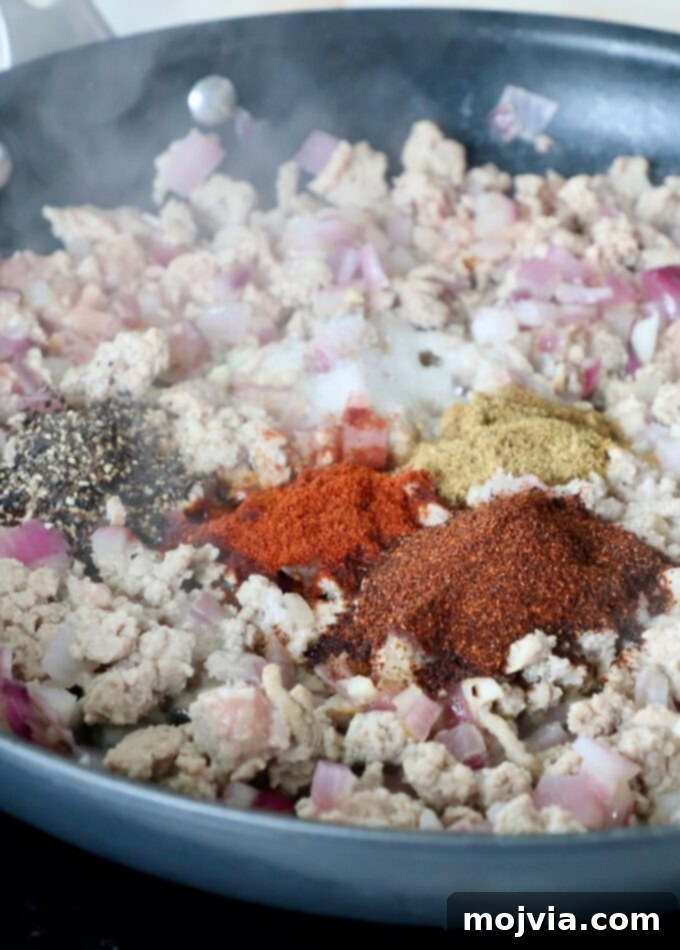 Ground turkey cooked through in a skillet, seasoned with chili spices.