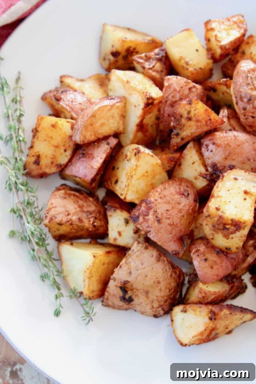 Overhead image of roasted cubed red potatoes on plate with thyme sprigs