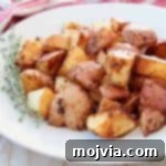 Crispy baked Cajun red potatoes on white plate with fresh thyme sprigs