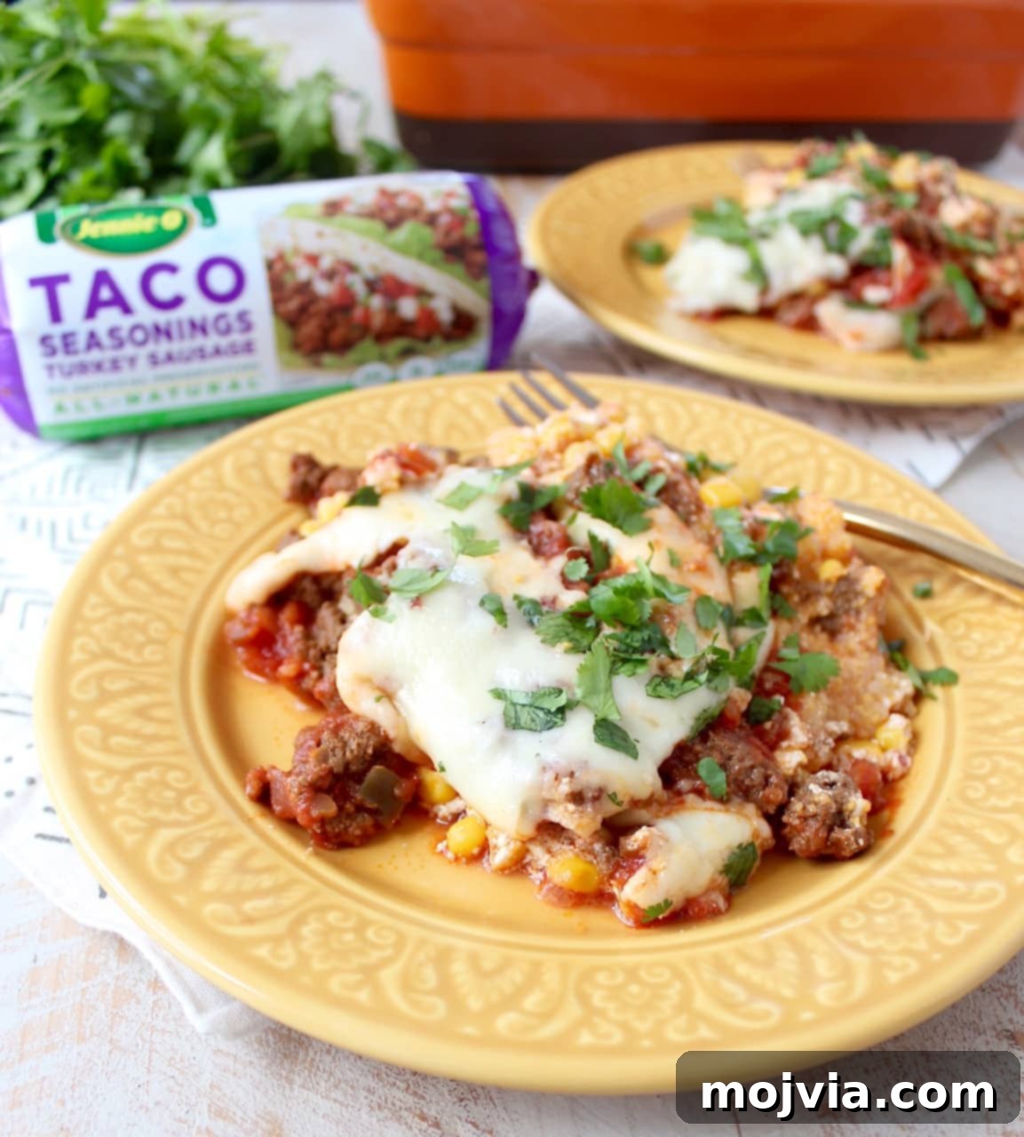 A vibrant gluten-free taco casserole, layered with taco-seasoned turkey, creamy polenta, sour cream, corn, salsa, and cheese, ready to be served.