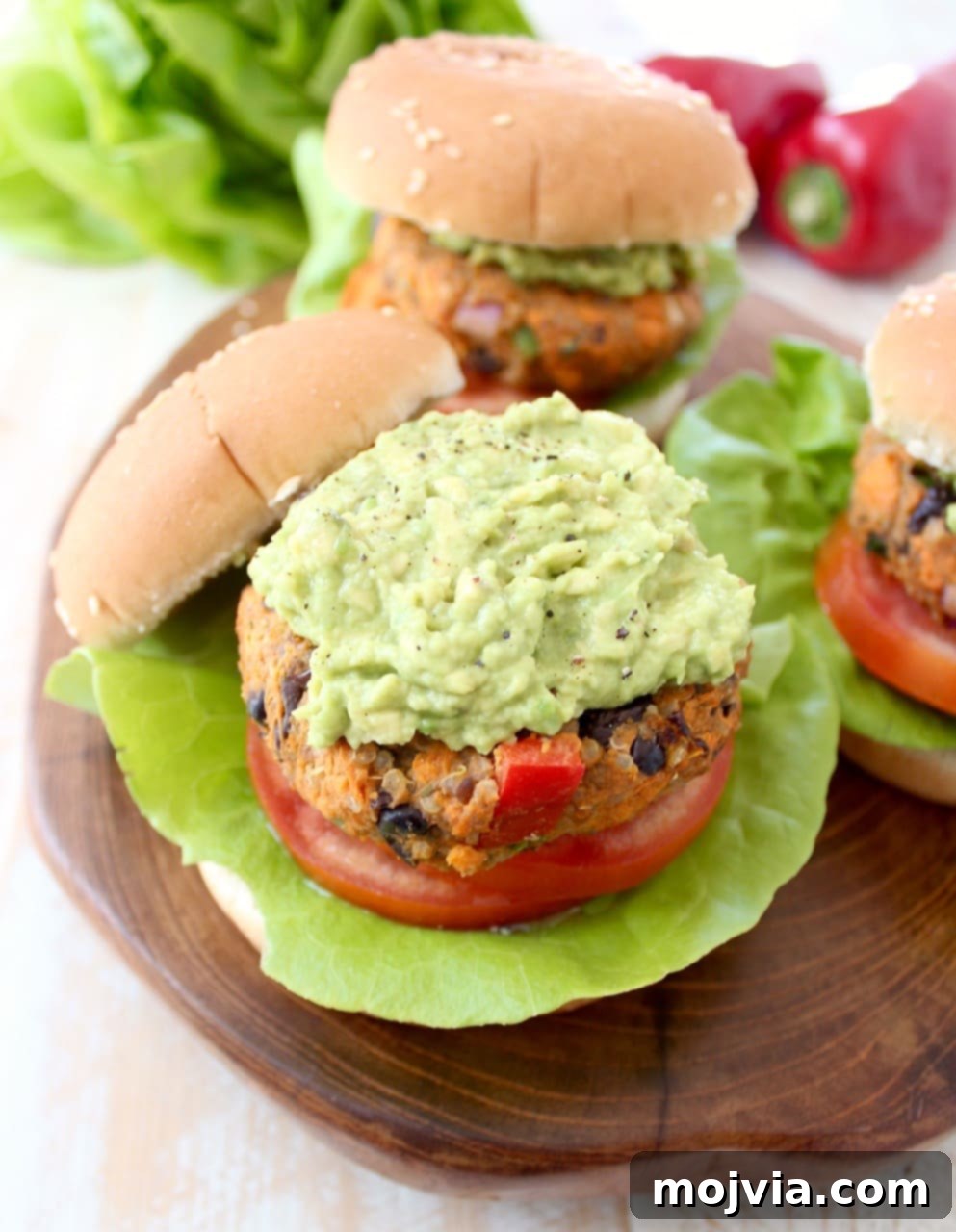 Quinoa, sweet potatoes, black beans & veggies are combined in this healthy, gluten free, black bean veggie burger recipe, which can be prepped ahead and stored in the refrigerator or freezer! Veggie Burgers topped with mashed Avocado on a wood board