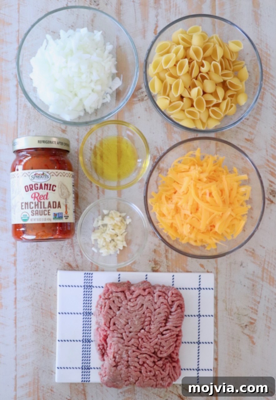 Ingredients for Enchilada Pasta laid out on a white wooden board