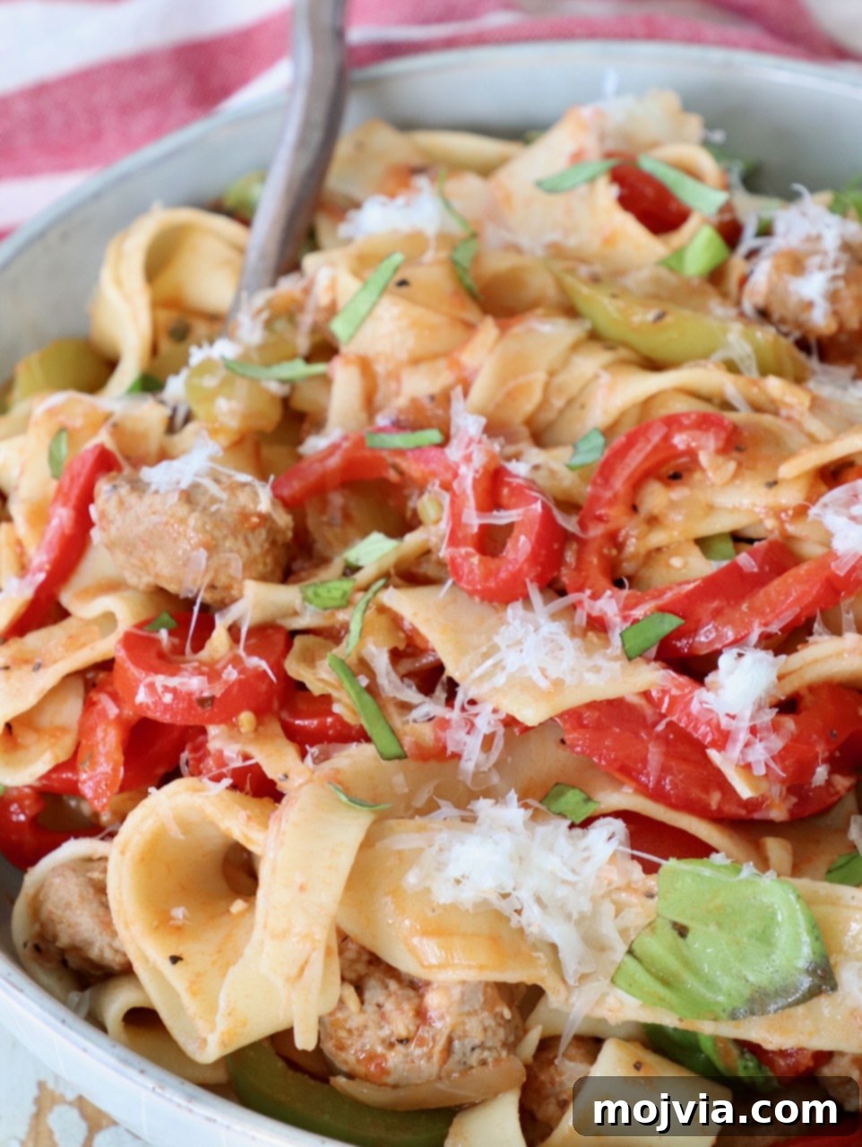 Boozy Italian Pasta 2 cooked pasta tossed with peppers, sausage and basil leaves in bowl with fork
