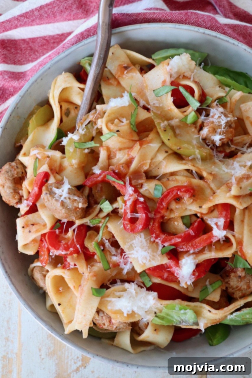 Boozy Italian Pasta 9 cooked pasta noodles tossed with peppers and sausage in bowl with fork