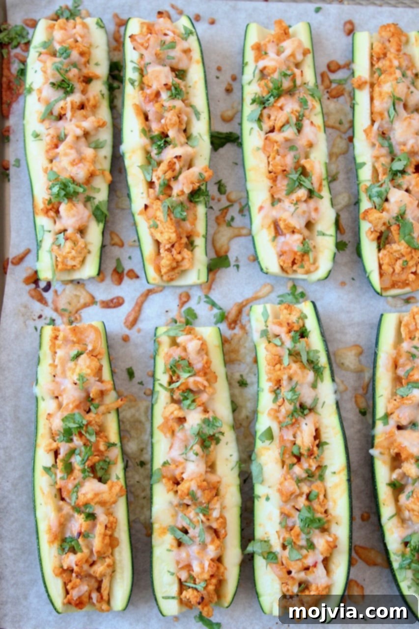 Tangy Buffalo Chicken Zucchini Bake 3 Buffalo Chicken Zucchini Boats on Parchment Lined Baking Sheet