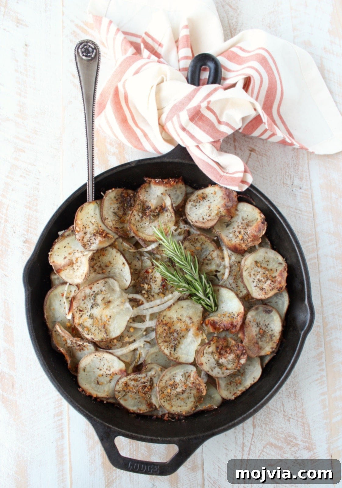A beautifully presented cast iron skillet filled with golden-brown, sliced and seasoned potatoes on a rustic wooden surface, ready to be served.
