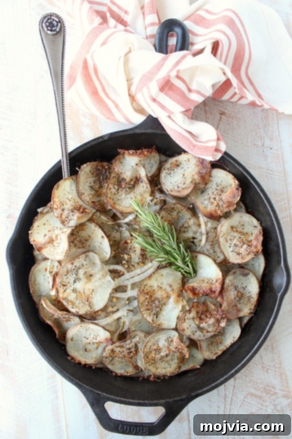 A cast iron skillet on a wooden surface, showing a single portion of layered and seasoned potatoes with a fork, emphasizing its individual serving appeal.