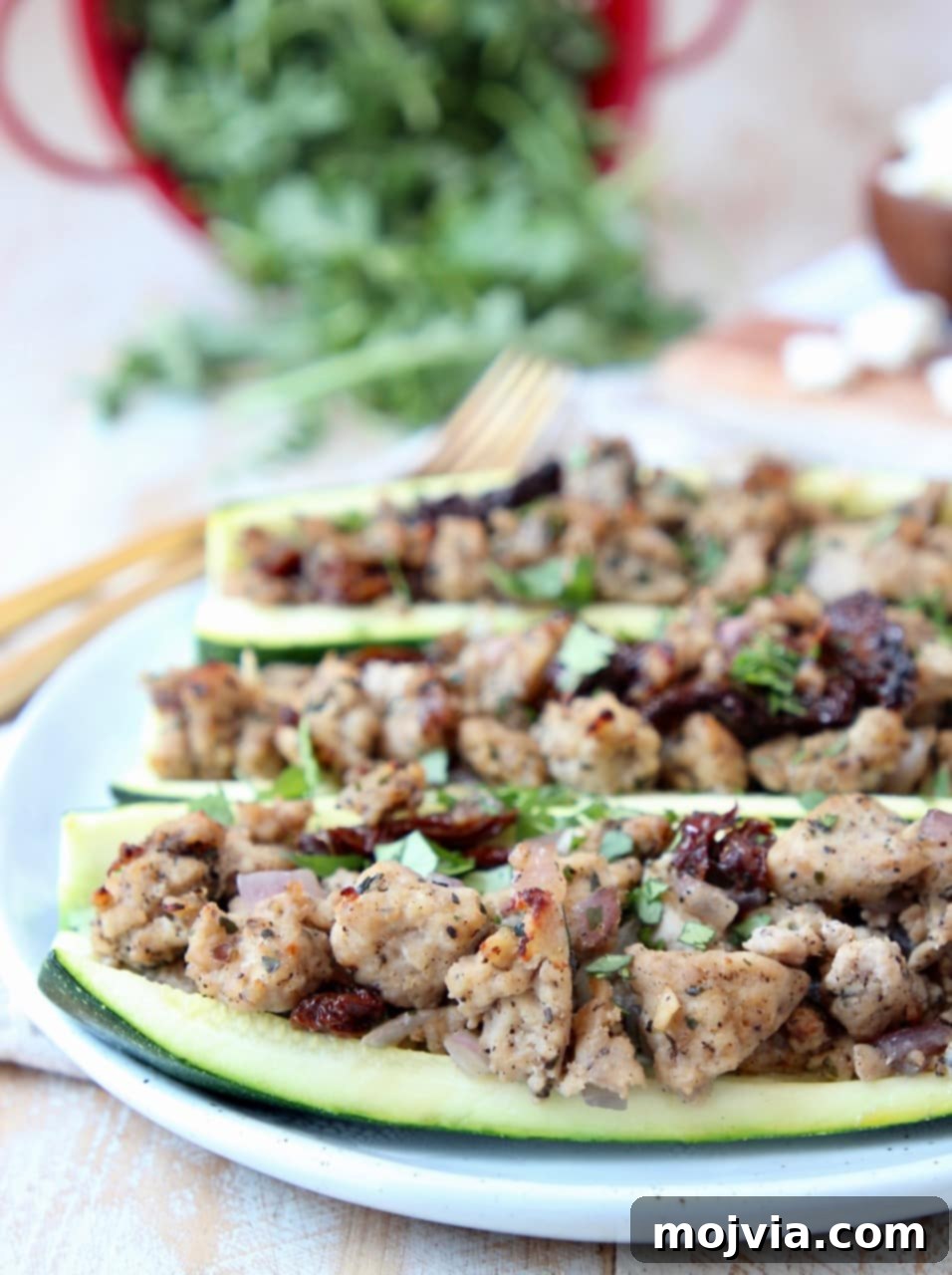 Zesty Greek Turkey Zucchini Boats 2 Greek Turkey Stuffed Zucchini Boats on white plate with gold forks in background
