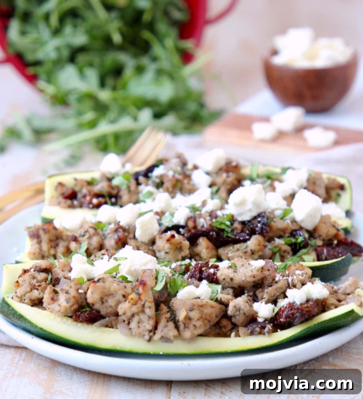 Zesty Greek Turkey Zucchini Boats 5 Ground Turkey, Sun Dried Tomato and Feta Cheese in hollowed zucchini halves on white plate