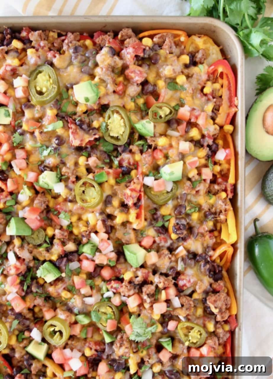 Low carb nachos on a baking sheet with avocado and jalapeno