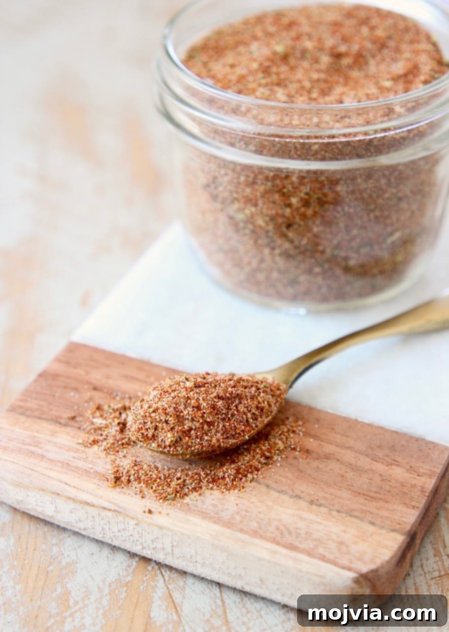 Homemade taco seasoning in mason jar on a marble cutting board with a spoon