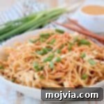 Pressure cooker chicken noodles with thai peanut sauce in bowl with diced green onions, shredded carrots and peanuts