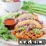 Spicy Cauliflower Tacos 2 Buffalo cauliflower tacos on corn tortillas with jalapeno carrot slaw and fresh cilantro on plate with small bowl of buffalo sauce