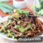 Black Pepper Beef and Broccoli with rice noodles and scallions on plate with chopsticks