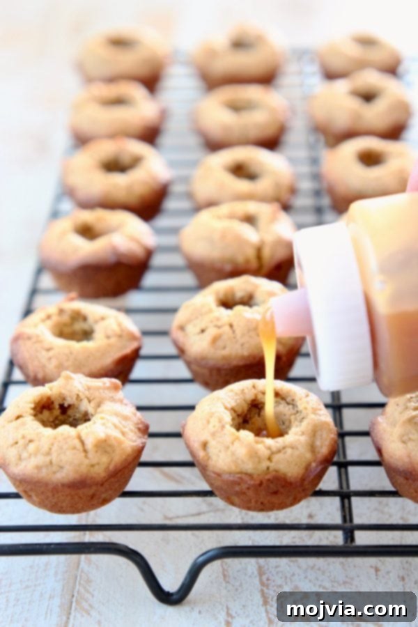 Plastic squeeze bottle with salted caramel sauce, filling mini pumpkin cookie cups on black wire baking rack